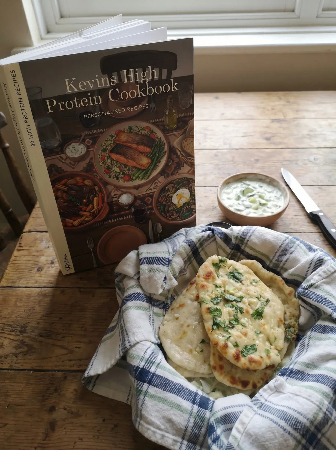 A personalised cookbook open on a kitchen counter next to fresh flatbreads